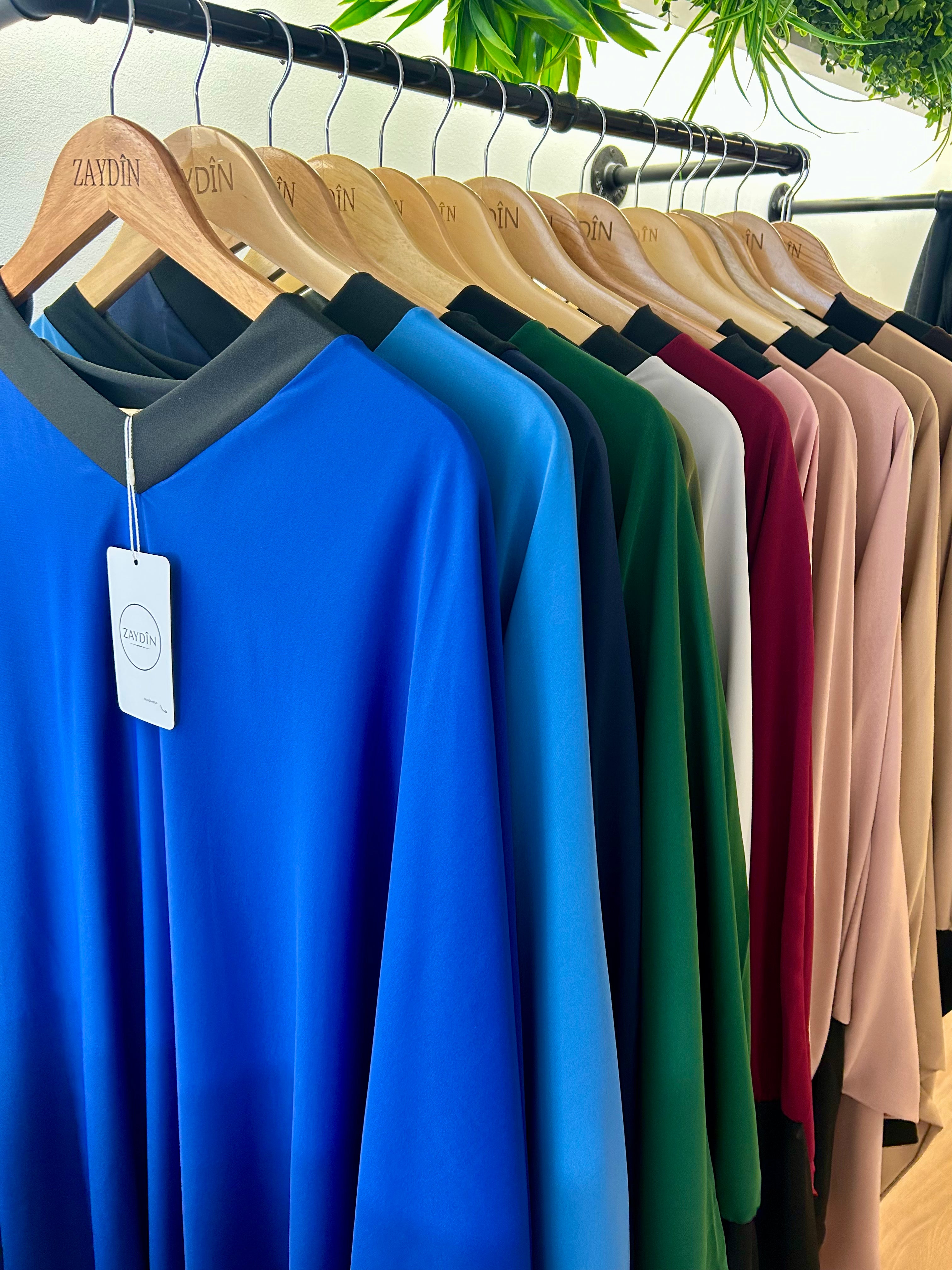 photos de abayas toutes les couleurs pendues sur des cintres